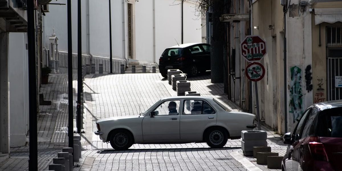 Classic car crossing an old urban street intersection with nostalgic architecture.