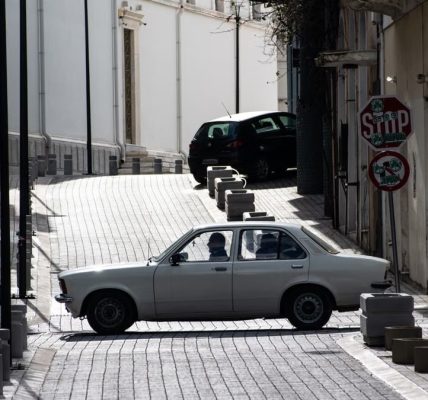 Classic car crossing an old urban street intersection with nostalgic architecture.