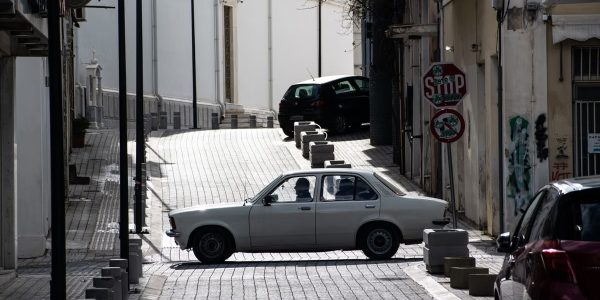 Classic car crossing an old urban street intersection with nostalgic architecture.
